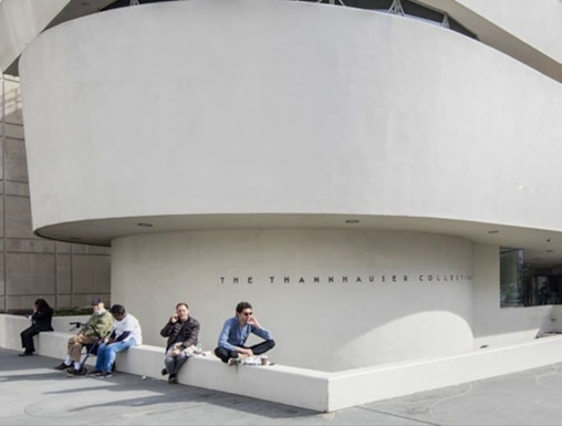 Guggenheim Museum exterior with visitors sitting near the Thannhauser Collection entrance.
