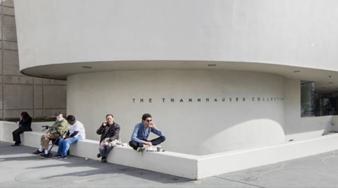 Guggenheim Museum exterior with visitors sitting near the Thannhauser Collection entrance.
