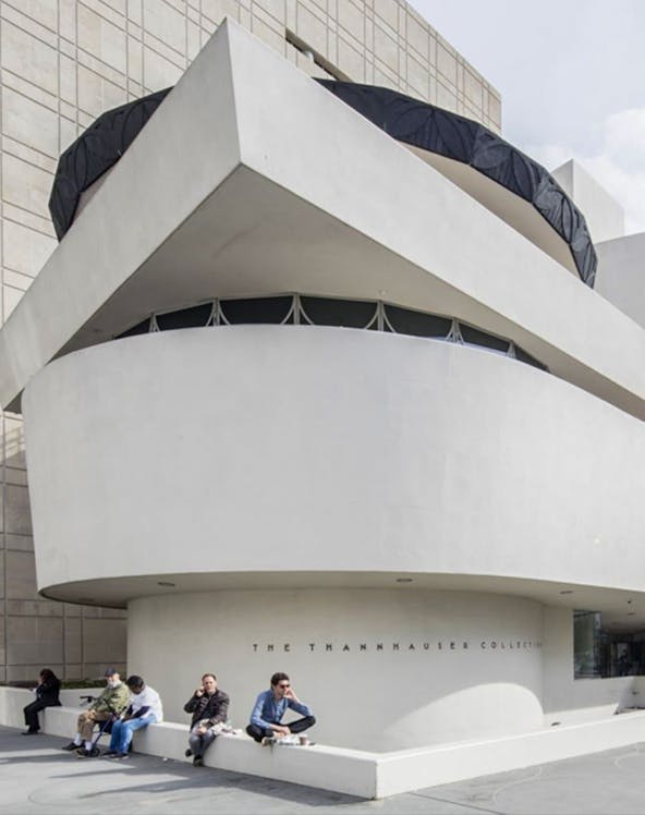 Guggenheim Museum exterior with visitors sitting near the Thannhauser Collection entrance.