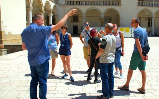 Group listening to a guide at Wawel Castle courtyard, Krakow.