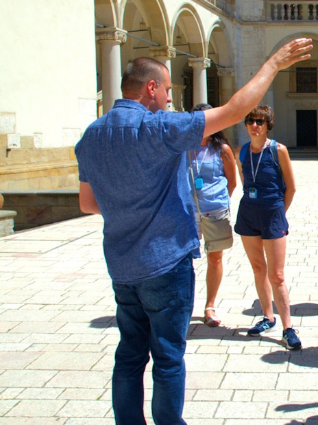 Group listening to a guide at Wawel Castle courtyard, Krakow.