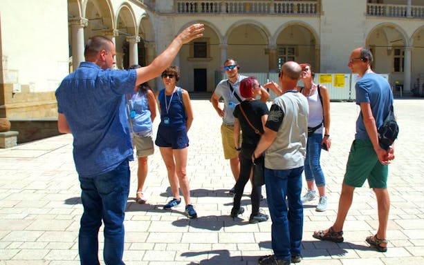 Group listening to a guide at Wawel Castle courtyard, Krakow.