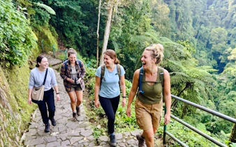 Hikers on a lush trail near Curug Cimahi waterfall, Bandung.
