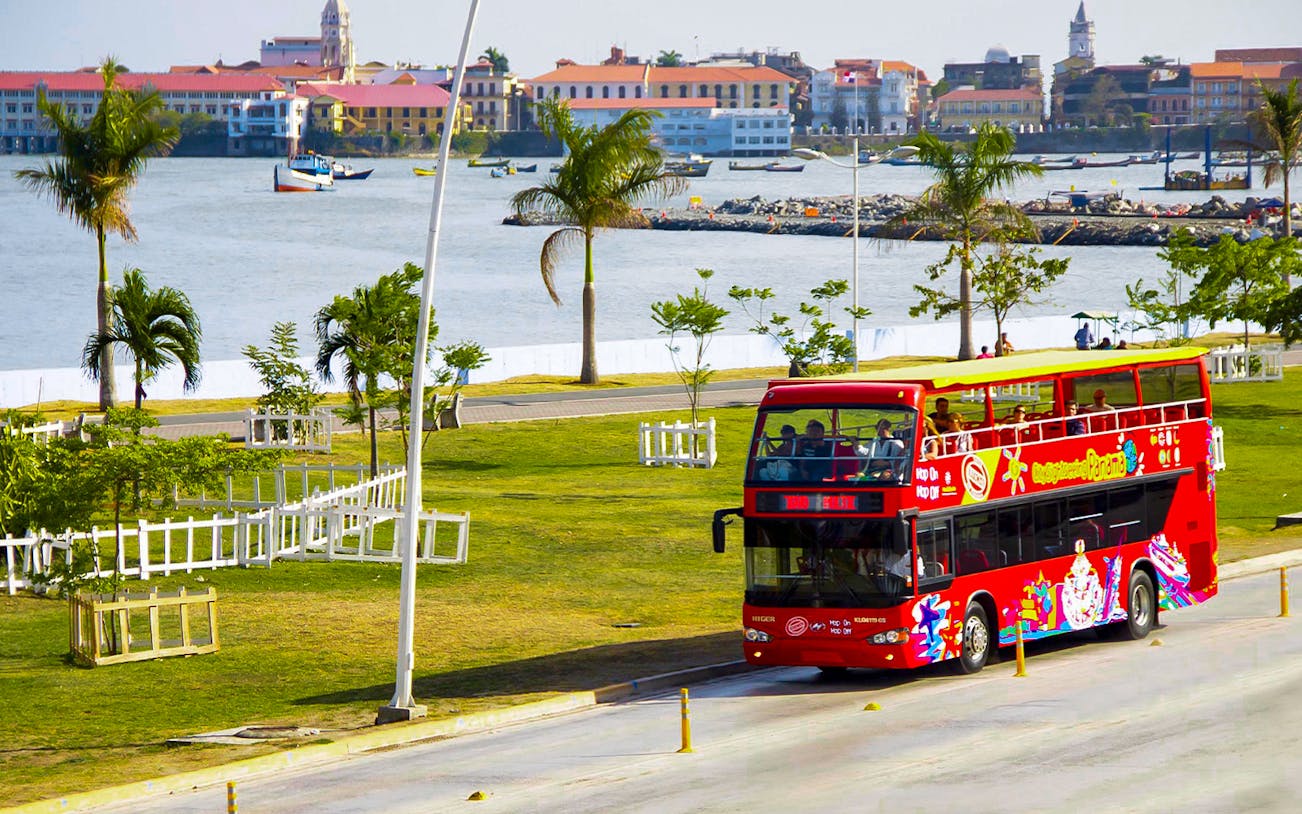 Red double-decker bus on Panama City Hop-On-Hop-Off Tour near waterfront.