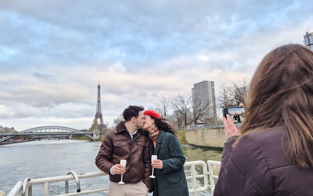 Couple kissing on Seine River cruise with Eiffel Tower in background, Paris, France.