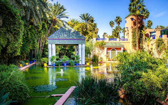 Jardin Majorelle pond with lush greenery and pavilion in Marrakech, Morocco.