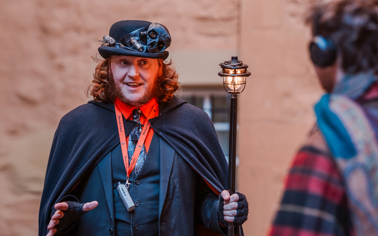 Tour guide in costume leading Edinburgh's Royal Mile ghost tour.