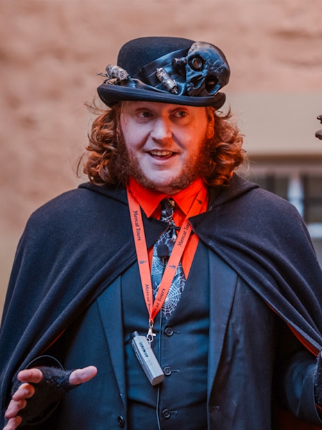 Tour guide in costume leading Edinburgh's Royal Mile ghost tour.