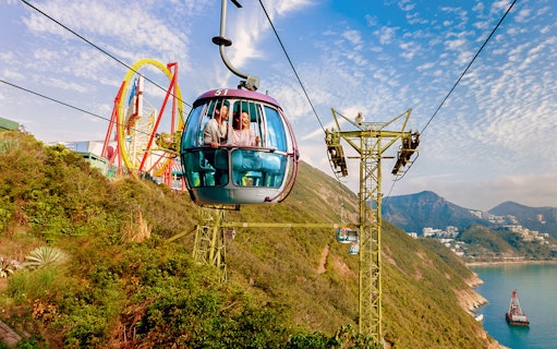 Guests riding a cable car at Ocean Park Hong Kong with scenic views of mountains and sea.