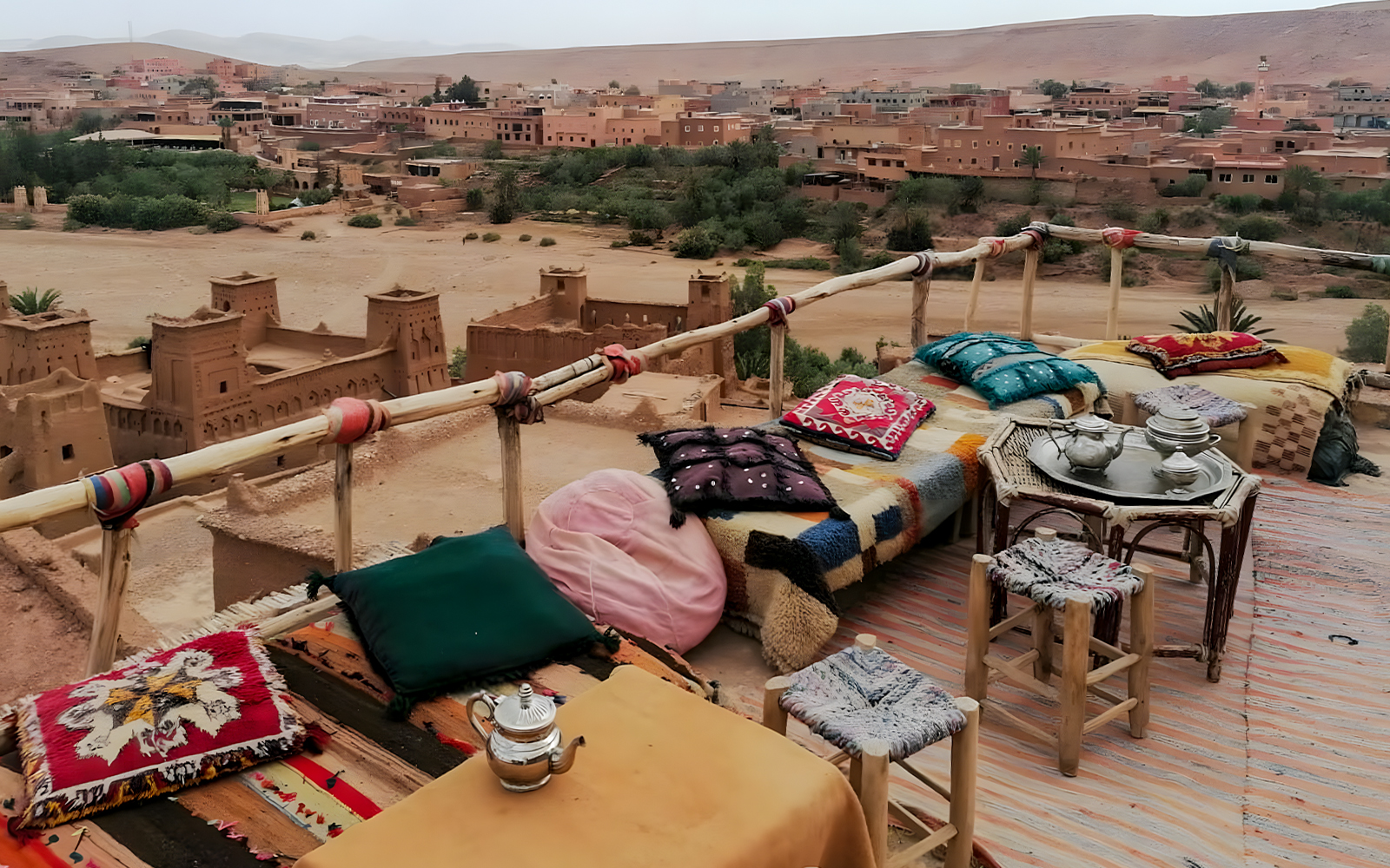 Rooftop view of Ait Benhaddou with traditional seating and tea set, seen on a day trip from Marrakech.