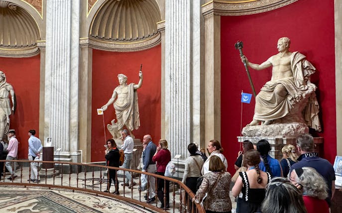 Visitors viewing classical statues in the Round Hall, Vatican Museums, Rome, Italy.