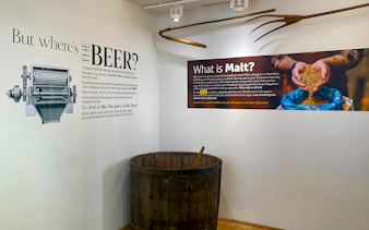 Prague Beer Museum exhibit on beer production with malt and brewing tools.