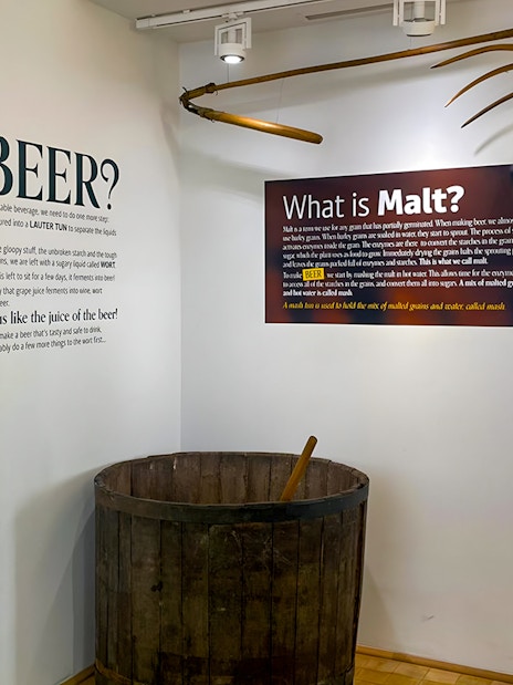 Prague Beer Museum exhibit on beer production with malt and brewing tools.