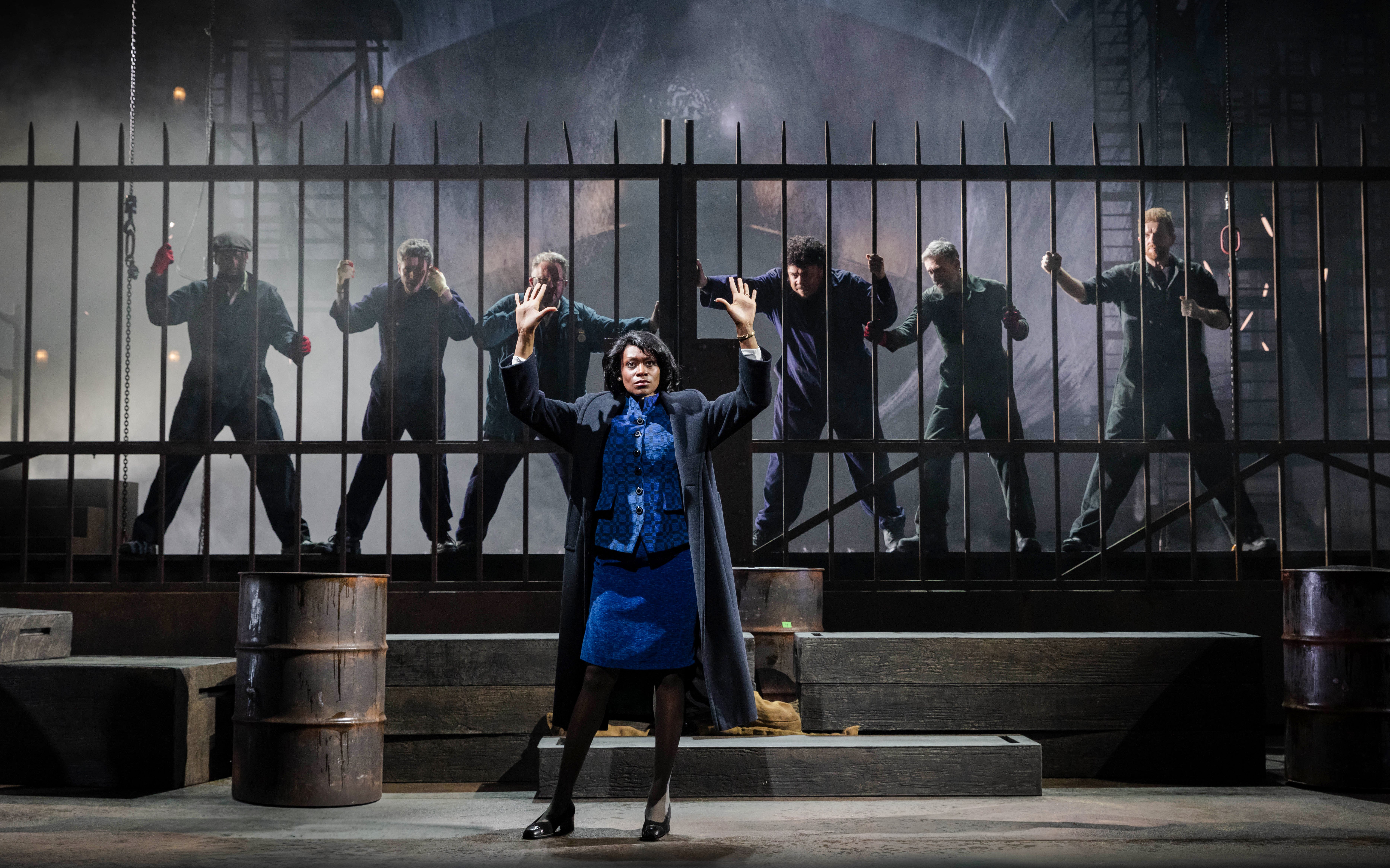 Stage scene from "The Last Ship" in Brisbane with actors behind a metal fence.