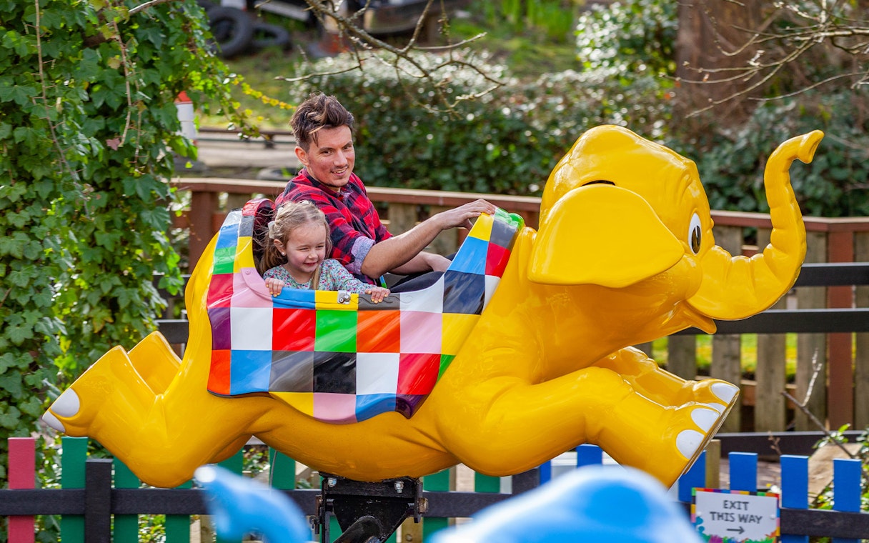 Family enjoying a colorful elephant ride at a theme park.