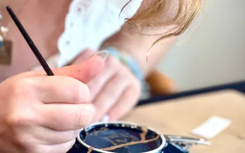 Repairing pottery with kintsugi technique in Shibuya workshop.