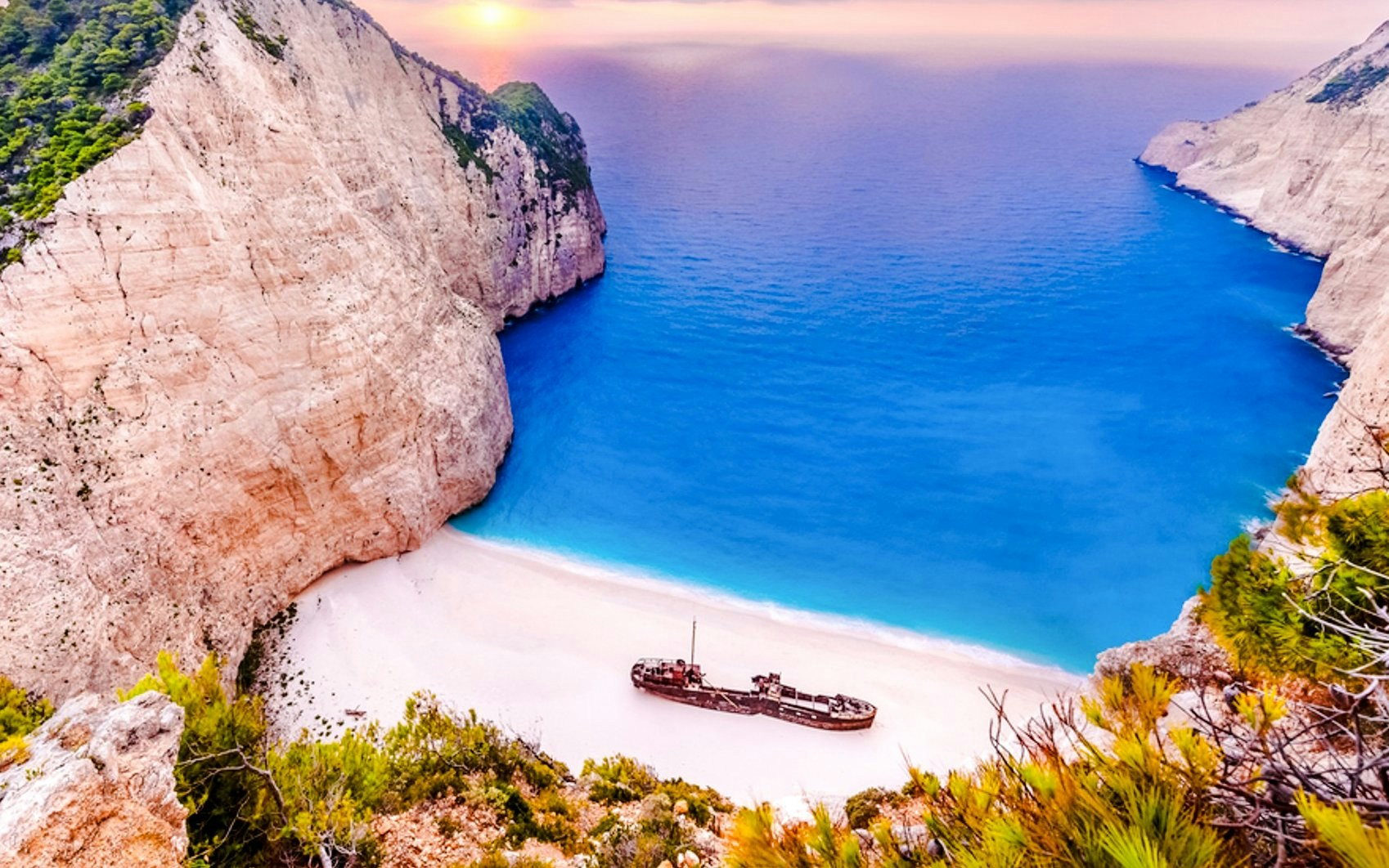 Navagio Beach shipwreck on sandy shore with cliffs and blue sea, Zante daily cruise.