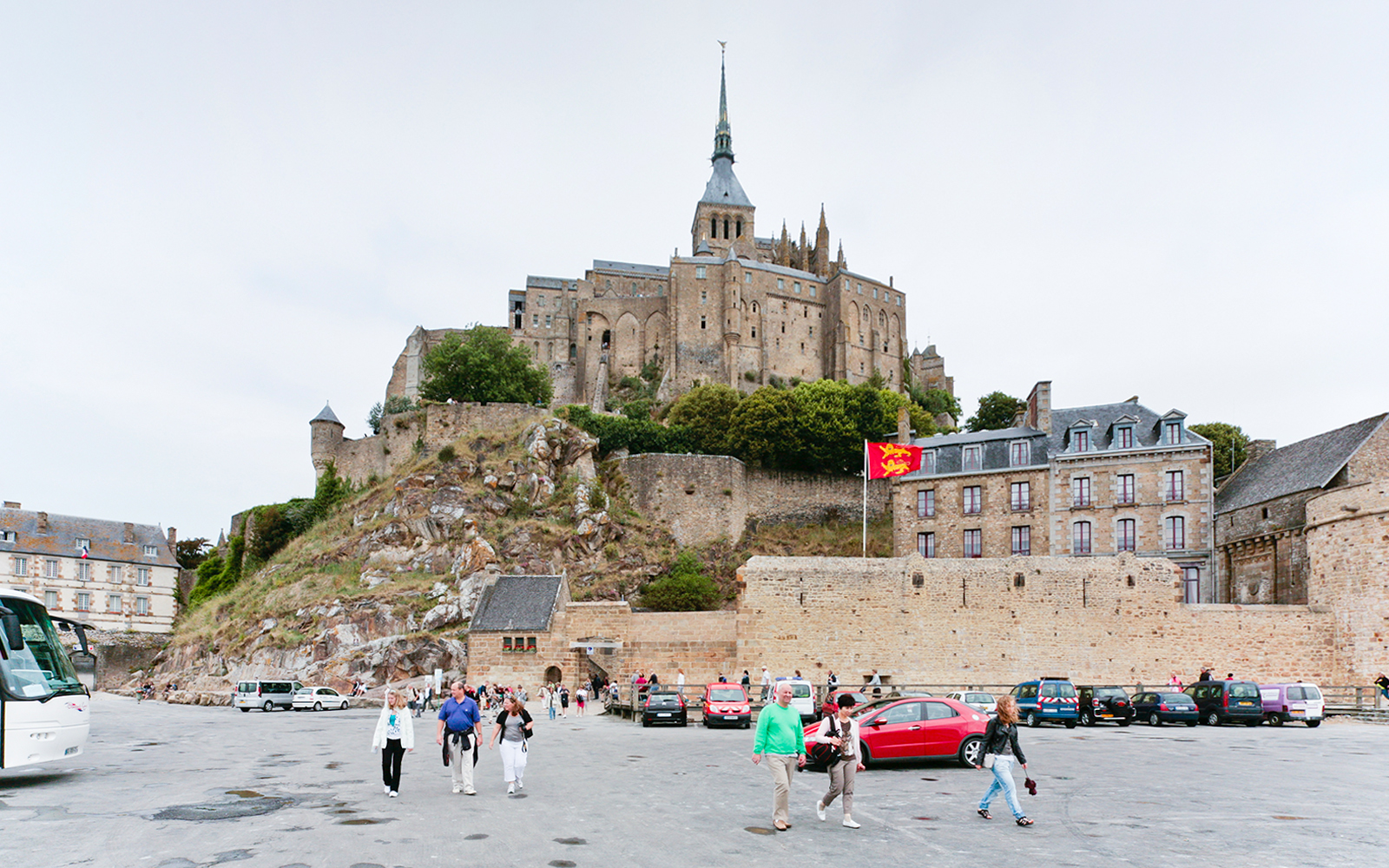 Mont Saint-Michel with tourists in the foreground, featuring the abbey and surrounding buildings.