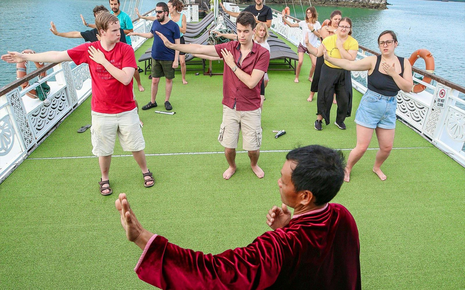 People practicing Tai Chi on a cruise deck in Halong Bay.