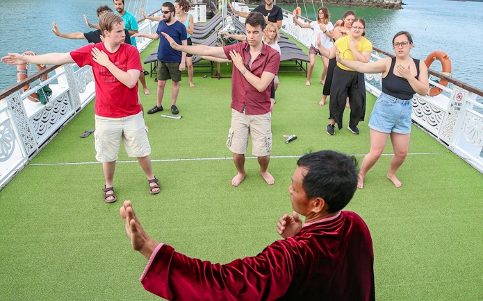 People practicing Tai Chi on a cruise deck in Halong Bay.