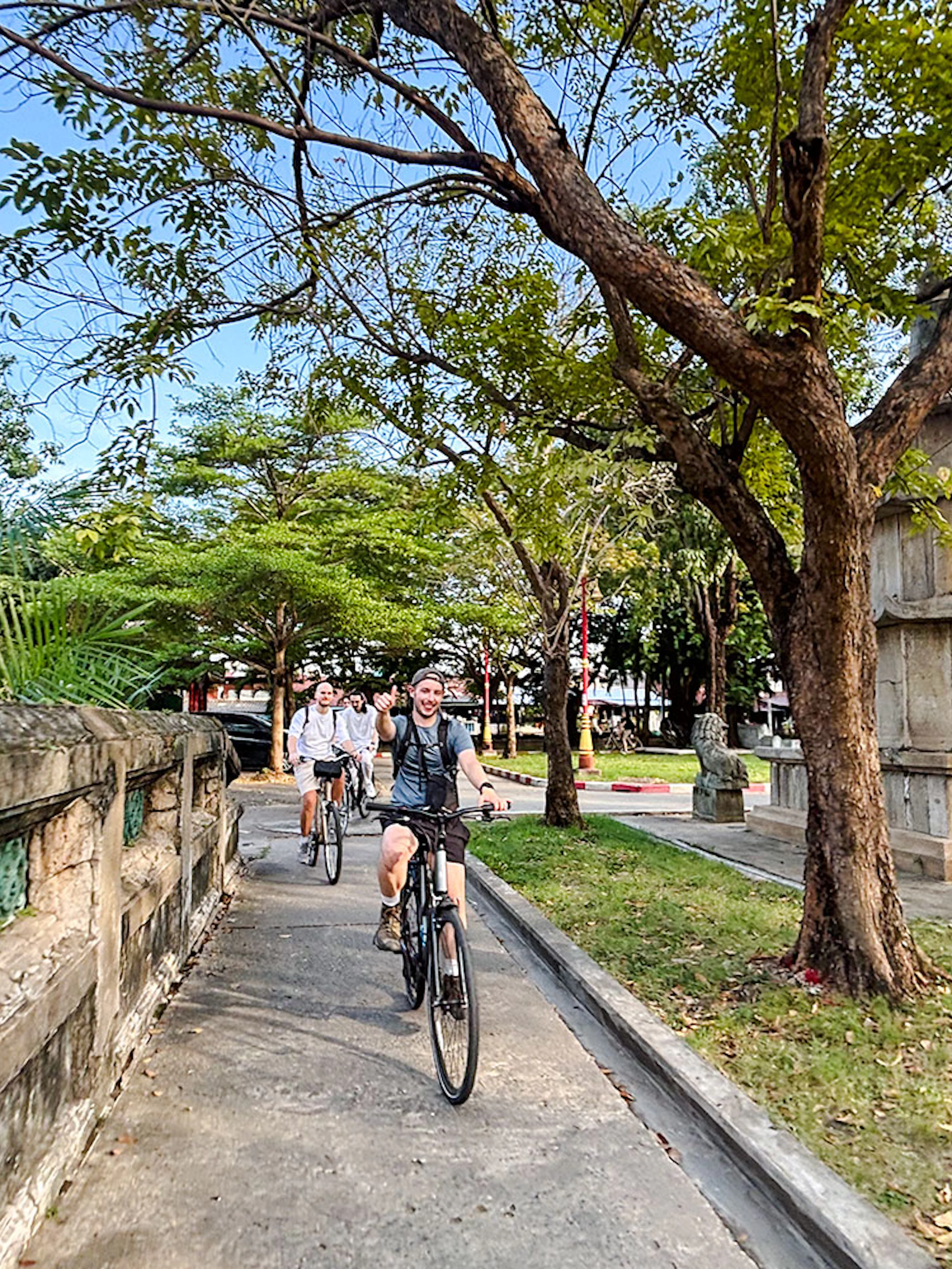 Tour group biking past a white chedi and temple on a backstreets tour in Bangkok.