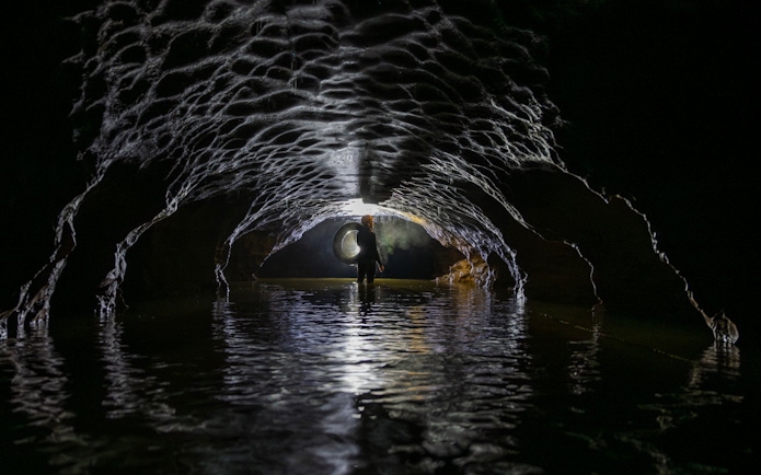 Person exploring Okohua Glowworm Cave with inner tube, Waitomo Experience.