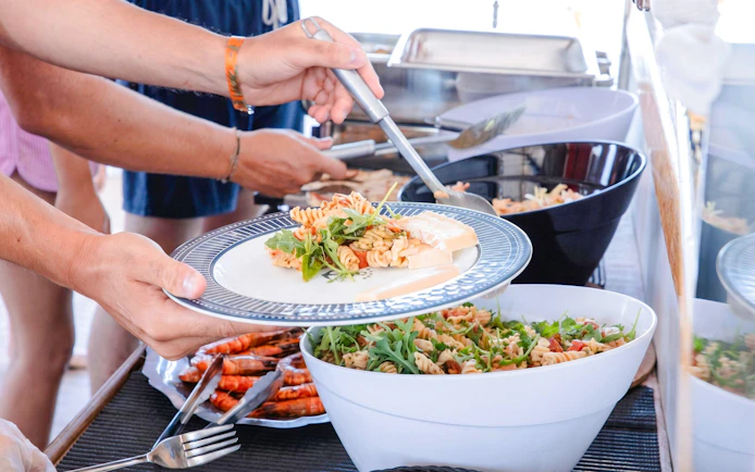 Guests serving pasta salad on a catamaran cruise near Lérins Island.