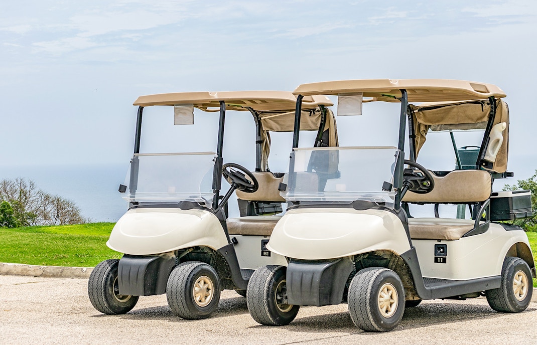 Golf carts parked on a scenic path overlooking the sea in Rome.