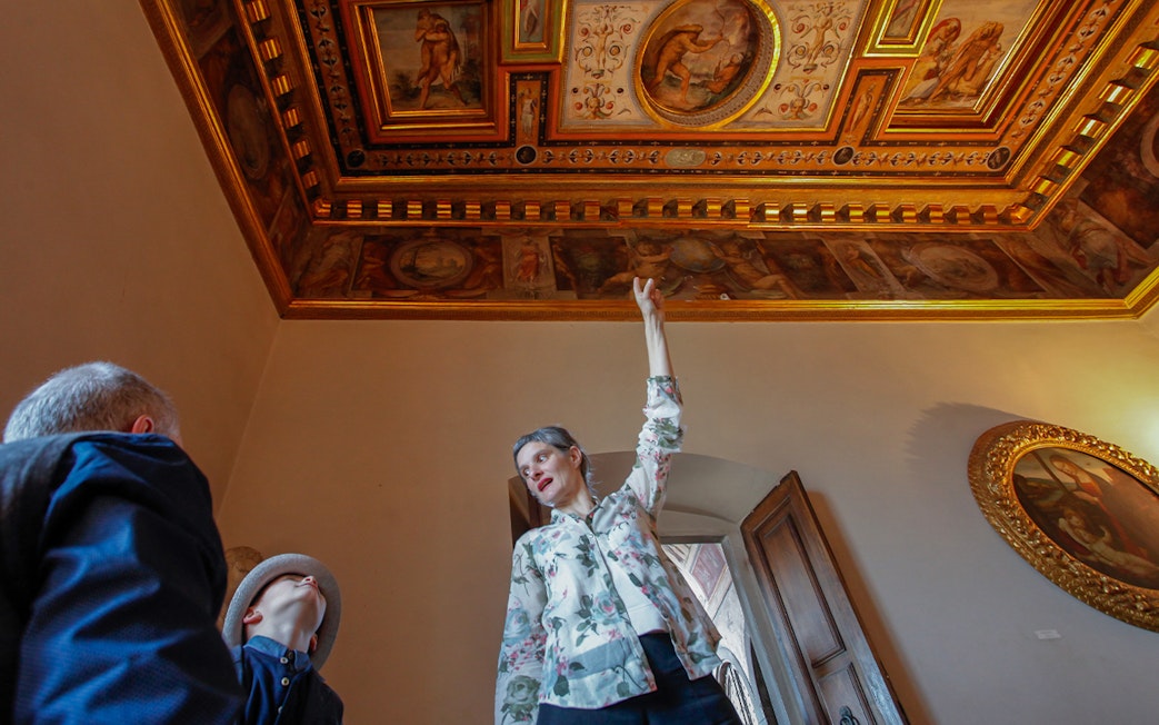 Guide explaining frescoes on the ceiling during Palazzo Vecchio Museum tour.