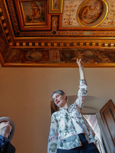 Guide explaining frescoes on the ceiling during Palazzo Vecchio Museum tour.
