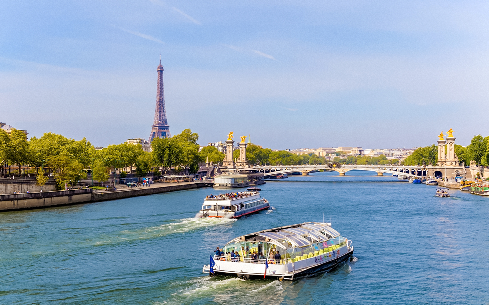 Seine River cruise boats near Eiffel Tower and Pont Alexandre III in Paris.