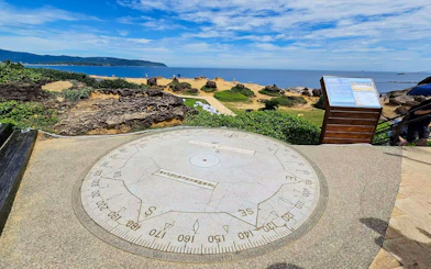 Large stone compass overlooking coastal landscape at Yehliu Geopark, New Taipei City, Taiwan.