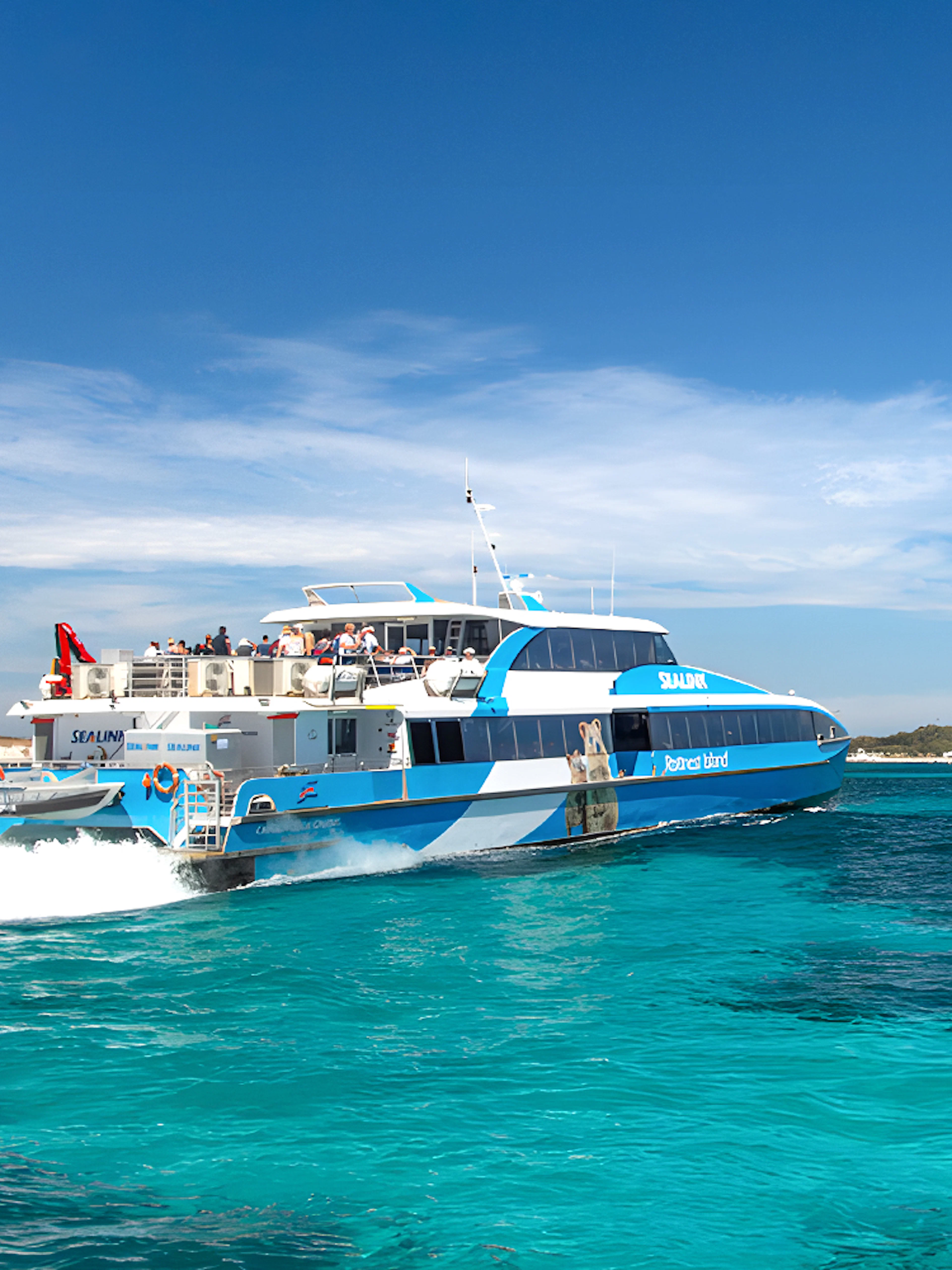 Tourists on a ferry near Rottnest Island with coastline view, part of the guided bus tour.