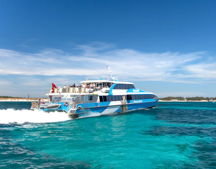 Tourists on a ferry near Rottnest Island with coastline view, part of the guided bus tour.