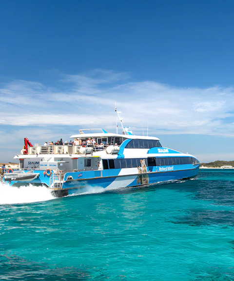 Tourists on a ferry near Rottnest Island with coastline view, part of the guided bus tour.