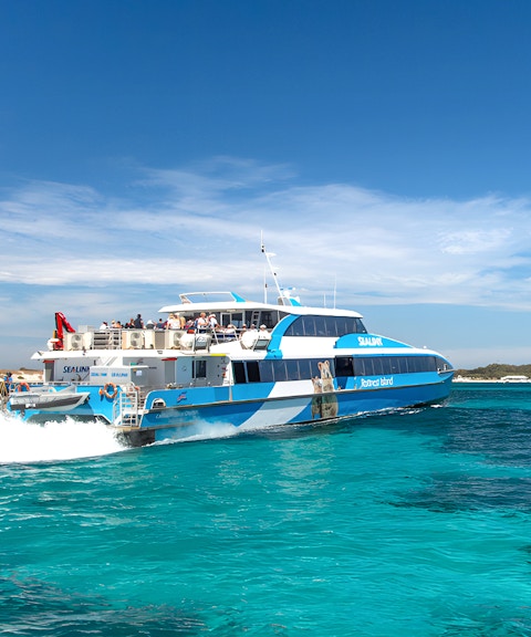 Tourists on a ferry near Rottnest Island with coastline view, part of the guided bus tour.