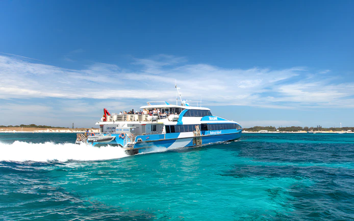 Tourists on a ferry near Rottnest Island with coastline view, part of the guided bus tour.