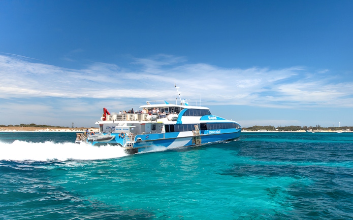 Tourists on a ferry near Rottnest Island with coastline view, part of the guided bus tour.