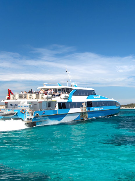 Tourists on a ferry near Rottnest Island with coastline view, part of the guided bus tour.