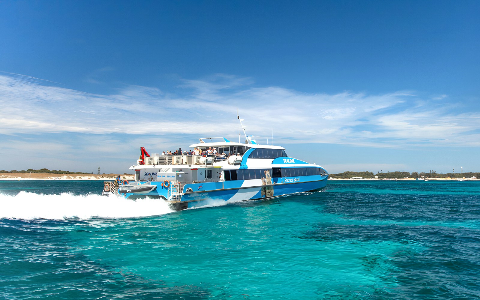 Tourists on Rottnest Island bus tour with coastline view, return ferry docked in Perth or Fremantle.