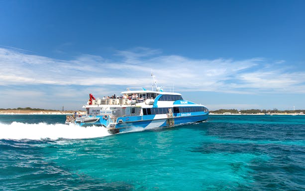 Tourists on a ferry near Rottnest Island with coastline view, part of the guided bus tour.