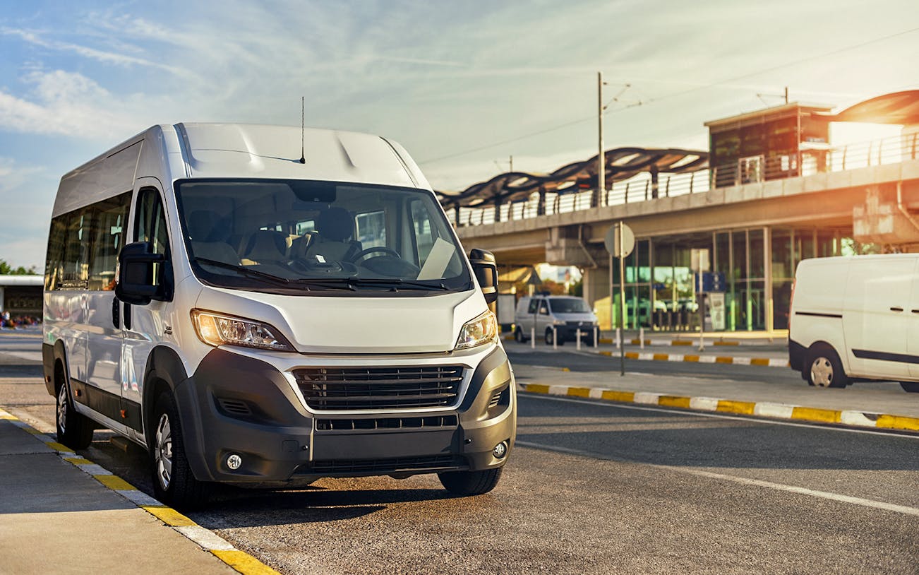 Shuttle bus parked near a station in Dubai, serving Atlantis, IMG, Dubai Parks, and Yas Island.