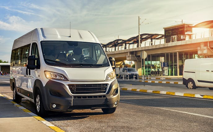 Shuttle bus parked near a station in Dubai, serving Atlantis, IMG, Dubai Parks, and Yas Island.