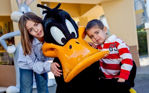 Children posing with a cartoon character at a theme park.