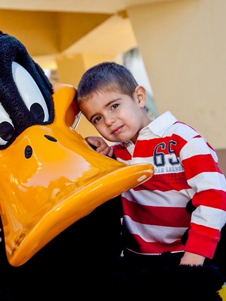 Children posing with a cartoon character at a theme park.