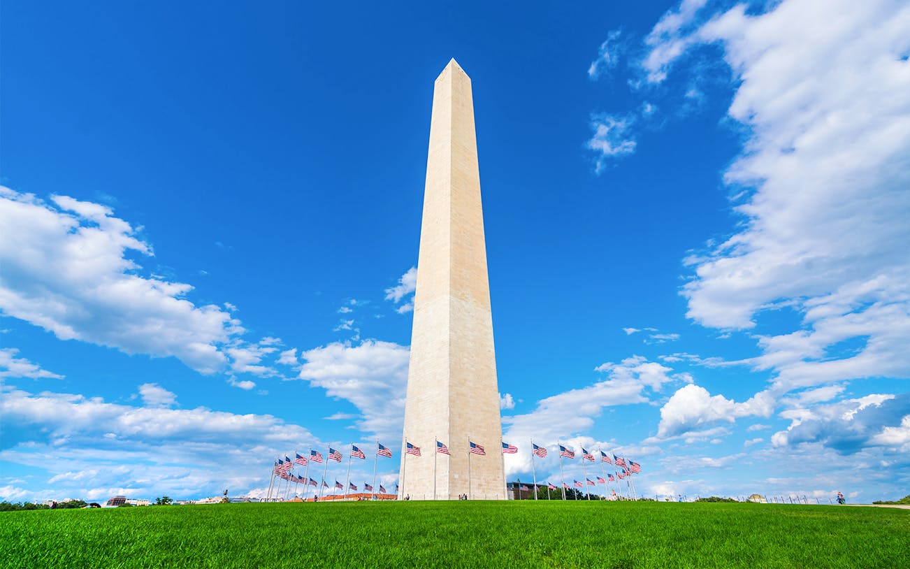 Washington Monument with flags and blue sky in Washington, D.C.