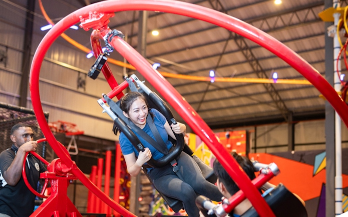 Woman enjoying a spinning ride at an indoor adventure park.