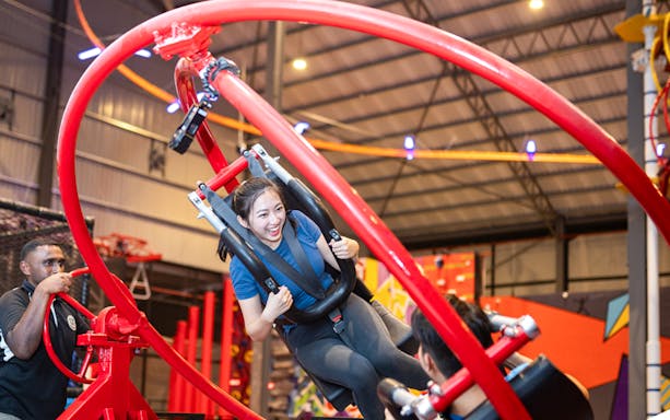 Woman enjoying a spinning ride at an indoor adventure park.