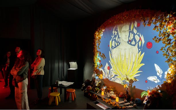 Visitors viewing Frida Kahlo artwork at immersive biography exhibit.