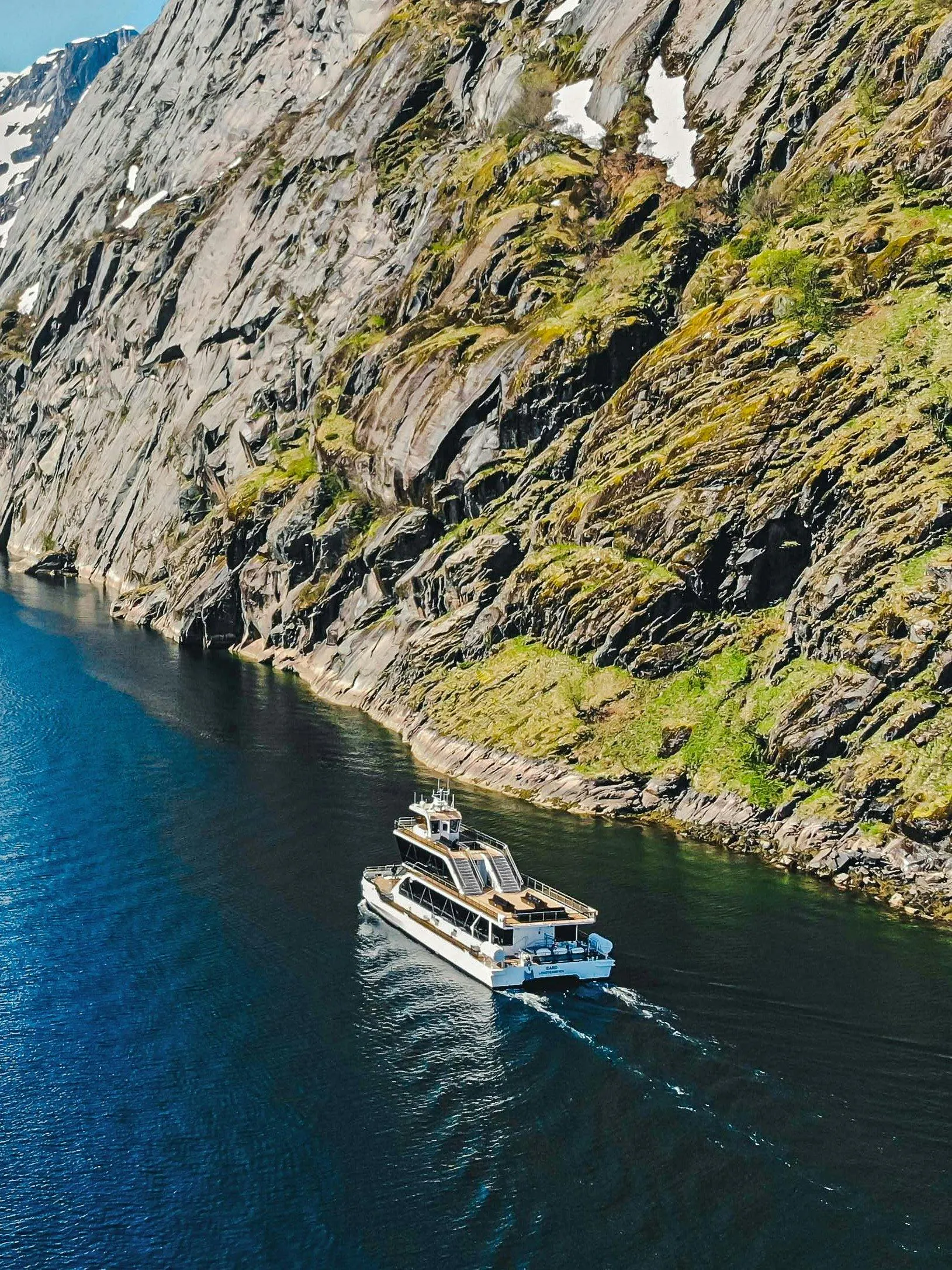 Cruise ship navigating Trollfjord's narrow waters, Lofoten, with steep rocky cliffs.